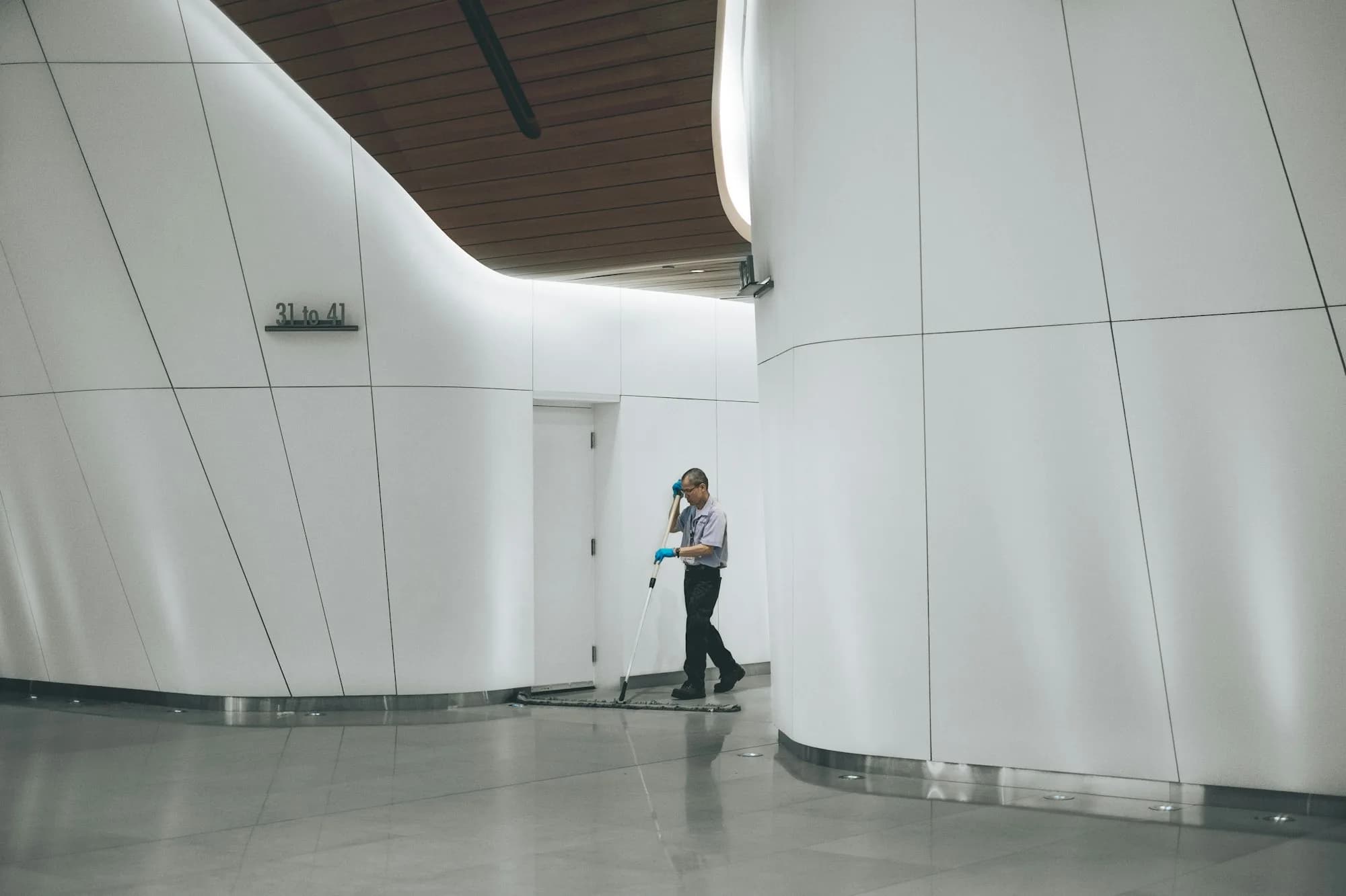 Reinigungskraft wischt den Boden eines hellen Bürofoyers