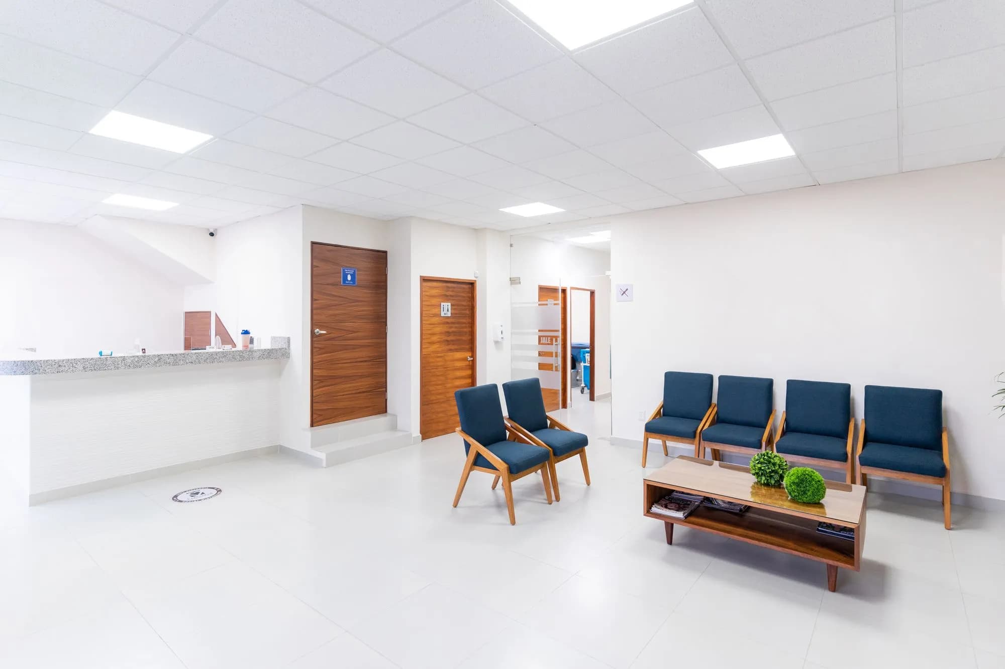Wartezimmer einer Praxis mit Empfangstresen und blauen Stühlen