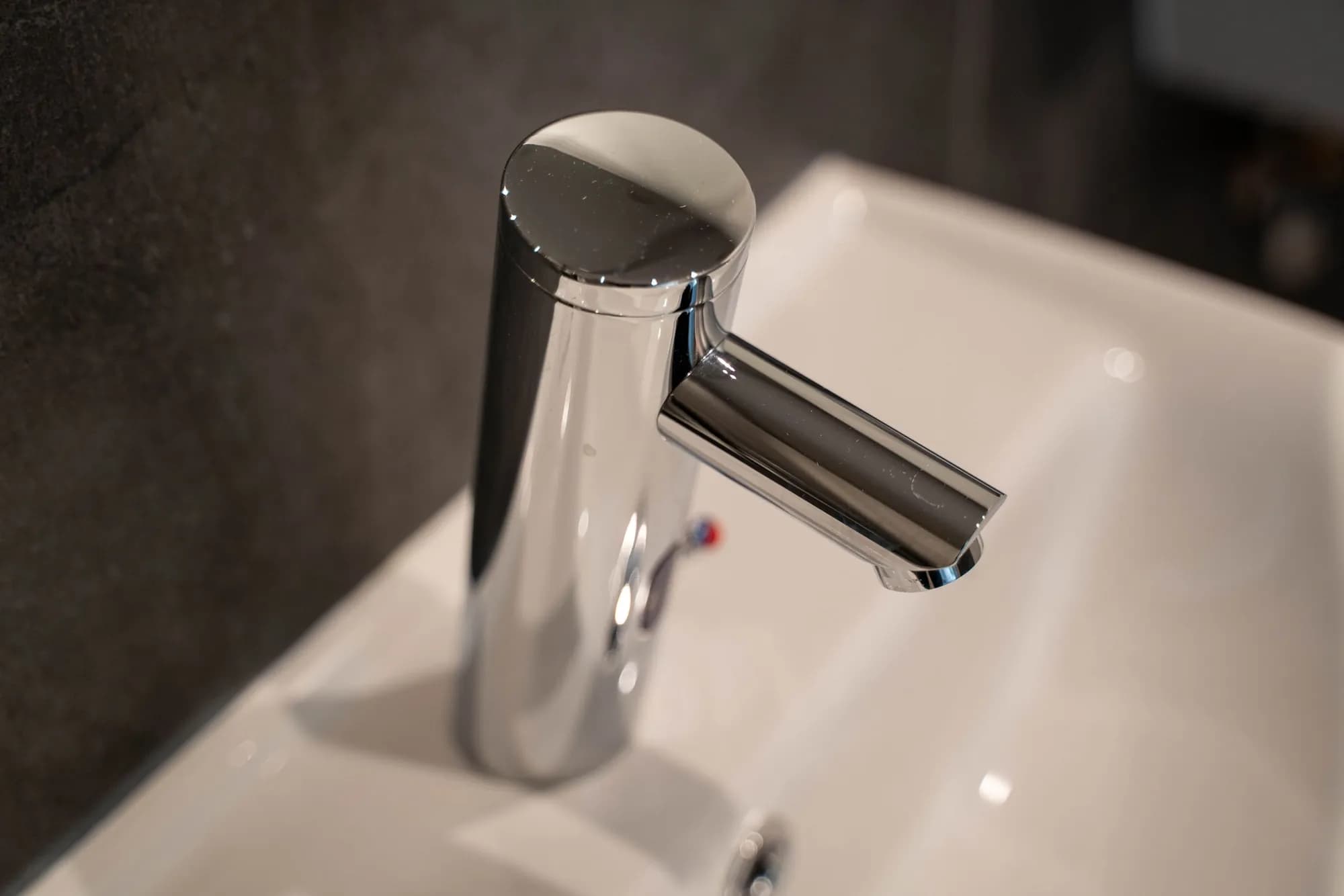 Makellos gereinigter Wasserhahn über einem weißen Waschbecken