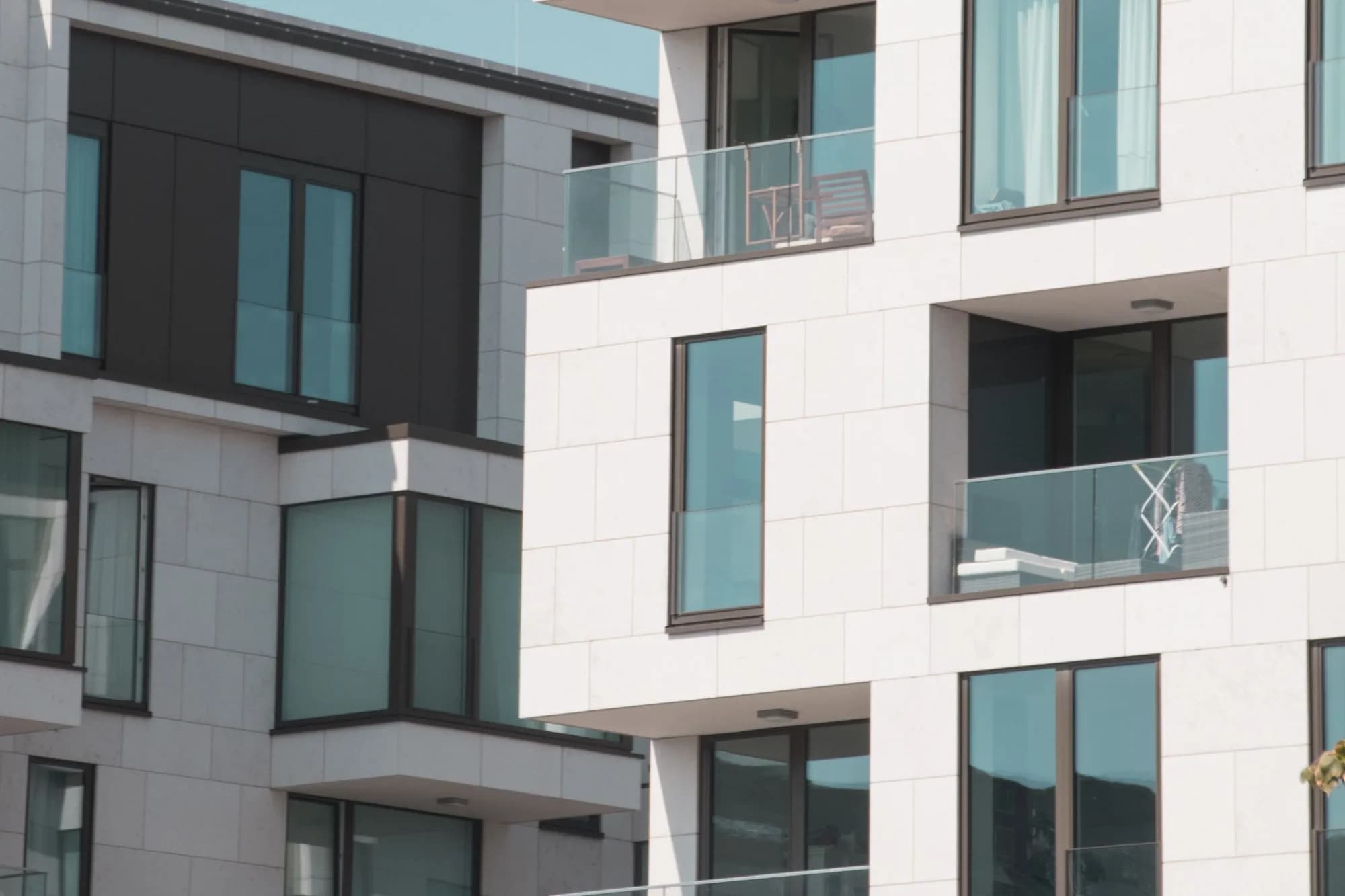 Fassade eines modernen Mehrfamilienhauses mit Balkonen und großen Fenstern
